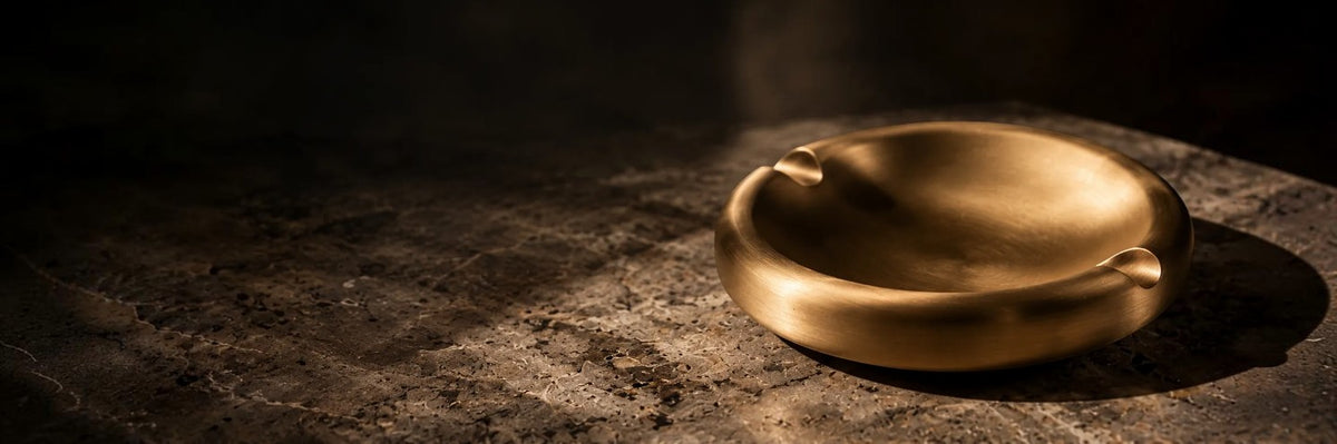 Born Brass satin gold solid brass ashtray on a stone surface